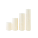 Set of four white candles of different sizes on a white background