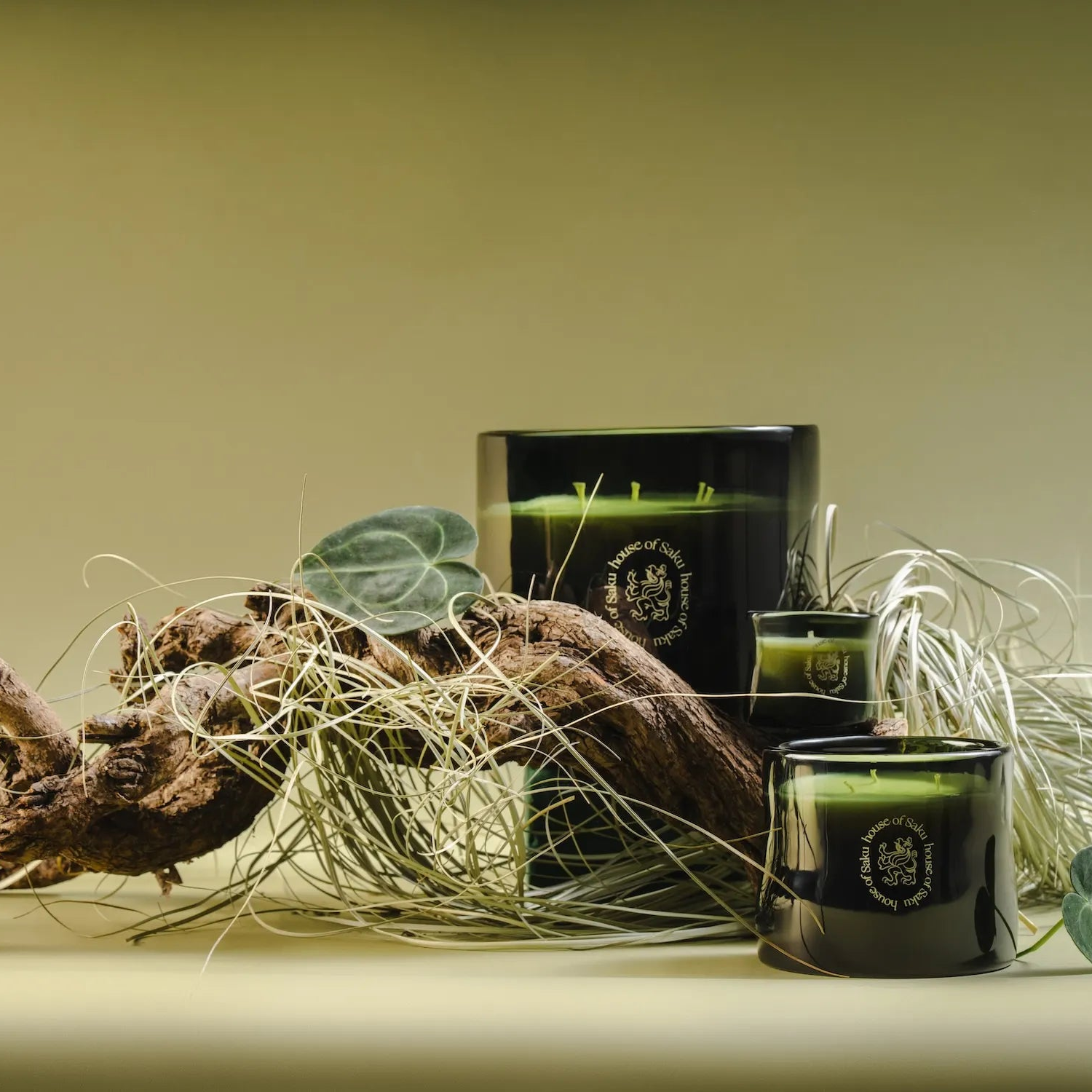 Three black candles with green wax on a surface with decorative elements.