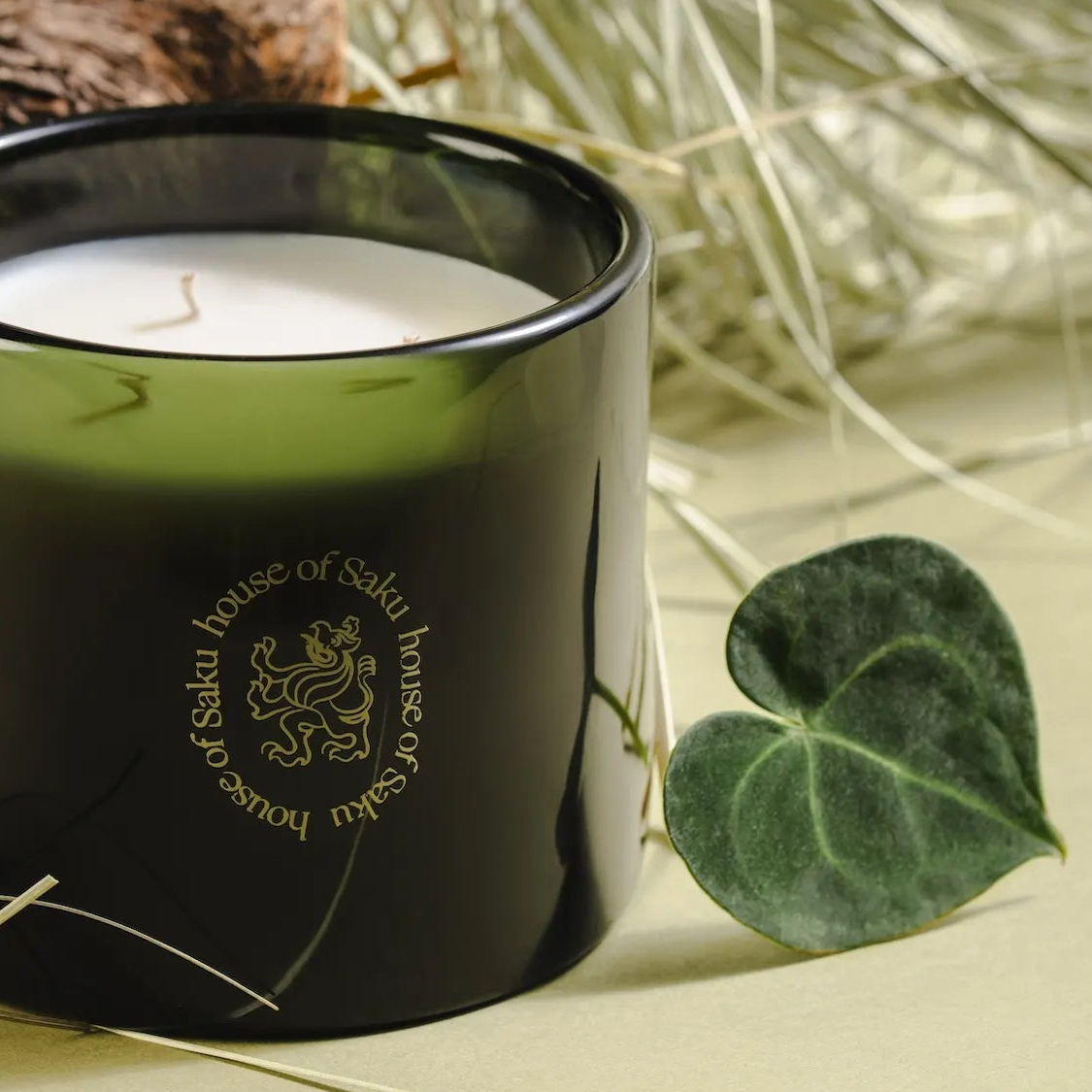 Black candle with 'house of Saku' branding on a light background with a leaf.